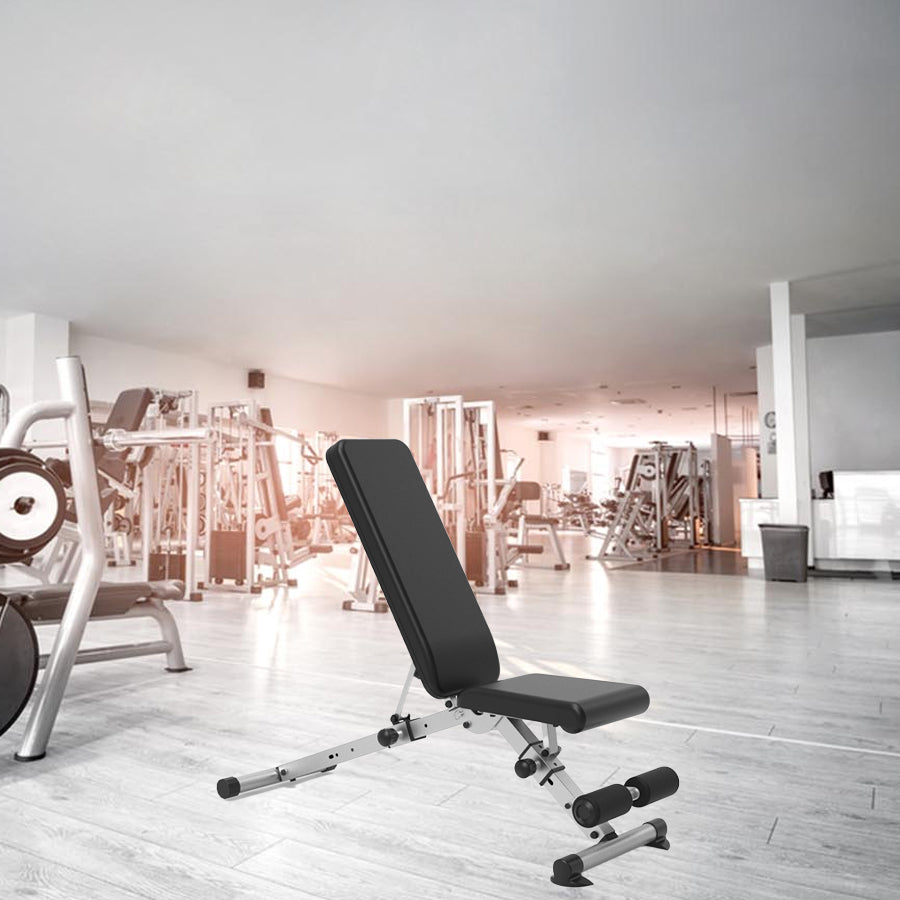 Black weight bench in a gym setting with equipment in the background