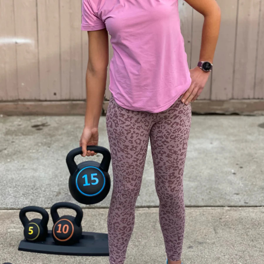 Person holding a 15-pound kettlebell with leopard print leggings and pink shirt.