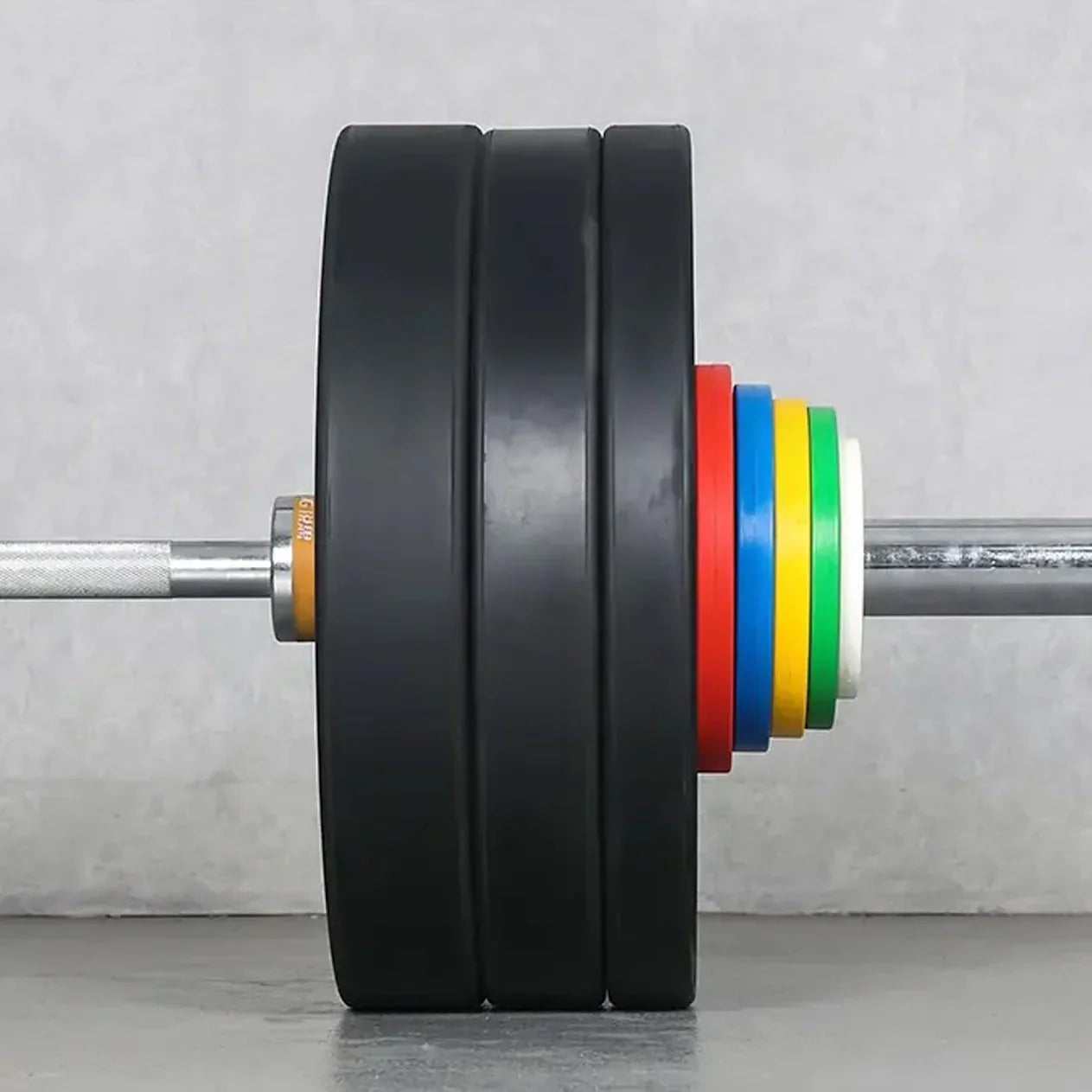 Barbell with weight plates and colorful bumper plates on a gray background