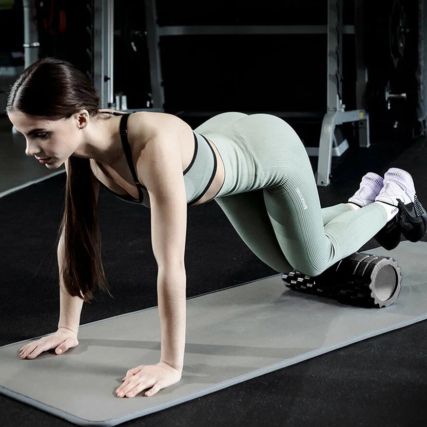 Woman in green athletic wear performing a push-up on a mat with gym equipment in the background