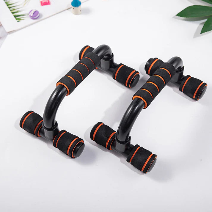 Black and orange exercise handles on a white surface with green leaves in the background