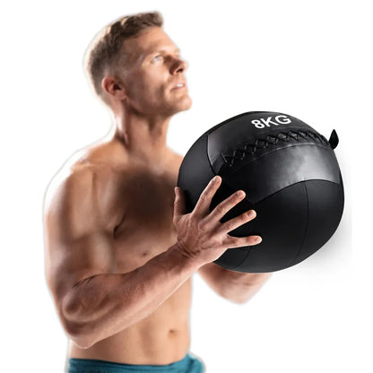 Man holding a 8KG medicine ball against a white background