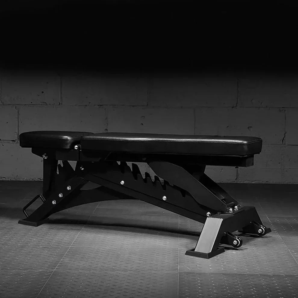 Black adjustable weight bench on a dark floor with a gray concrete wall background